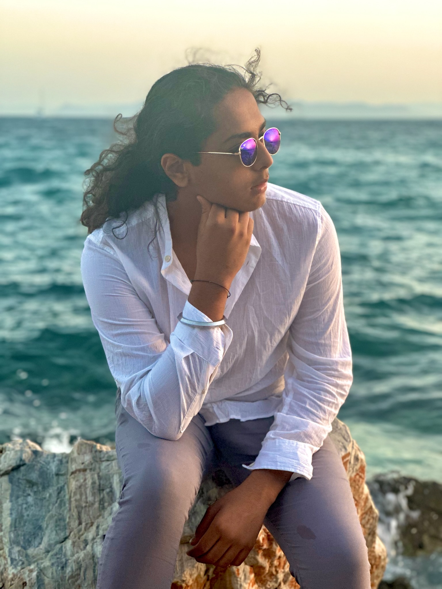 Aryan Rohira by a serene Greek waterfront with blue waters